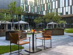 a table and chairs in a courtyard with a building at Novotel Living Almaty Jetisu in Almaty