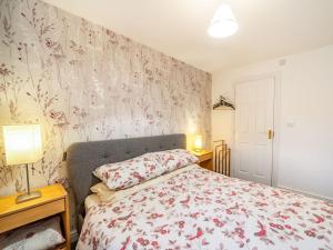 una camera da letto con un letto e carta da parati floreale di Monument Way a Ulverston