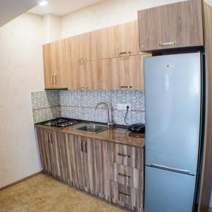 a kitchen with wooden cabinets and a stainless steel refrigerator at Cozy Apartment in Bakuriani in Bakuriani