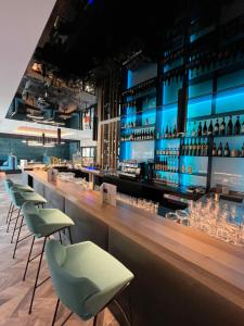 - un bar avec des chaises vertes et un comptoir avec des bouteilles de vin dans l'établissement Aqua Blu Hotel, à Bad Füssing