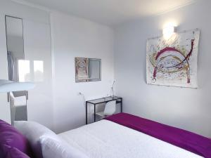 a white bedroom with a bed and a painting on the wall at Casa Sol y Mar in Garachico