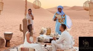 a group of people sitting around a table in the desert at Sahara Majestic Luxury Camp in Merzouga