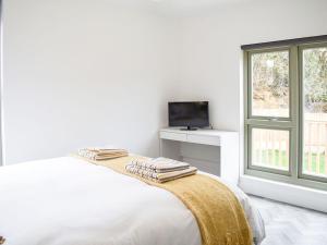 a white bedroom with a bed and a television at Deerson Barn in Wingham