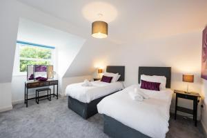 two beds in a room with two tables and a window at Blaisedell House by Cliftonvalley Apartments in Bristol