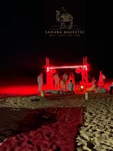 een groep mensen die 's nachts op een strand staan bij Sahara Majestic Luxury Camp in Merzouga