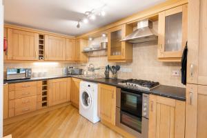 cocina con armarios de madera, lavadora y secadora en Blaisedell House by Cliftonvalley Apartments en Bristol