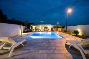 a swimming pool with two chairs and a house at Villa 7 in Međugorje
