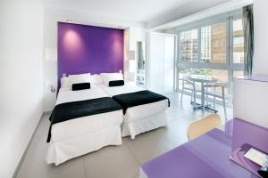 - une chambre avec un grand lit et un mur pourpre dans l'établissement Hotel Brisa, à Benidorm