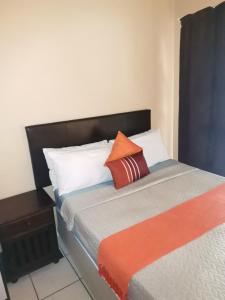a bed with orange and white pillows on it at Mavundla guest house in Richards Bay