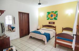 1 dormitorio con 2 camas, TV y espejo en Pousada Brazish, en Paraty