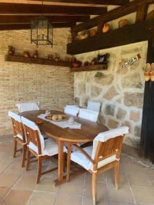 a wooden table with chairs and a stone wall at Casa Rural LOS TINES in Bustarviejo