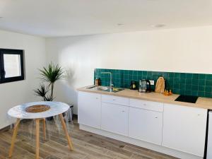 a kitchen with white cabinets and a sink and a table at Bel air 2 in Fougeré