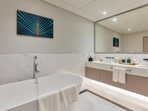 Luxury Living & Views -St Regis High Floor Suite 4 by Exclusive Holiday Homes في دبي: حمام أبيض مع حوض ومغسلة
