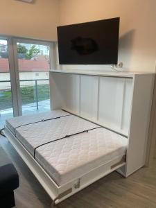 a white bed with a tv on top of it at Moonlight Apartment in Siófok