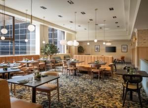 un restaurante con mesas, sillas y ventanas en Leonardo Royal Hotel Birmingham en Birmingham