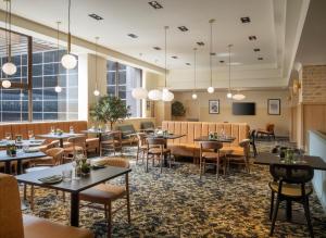 バーミンガムにあるLeonardo Royal Hotel Birminghamのテーブルと椅子と窓のあるレストラン