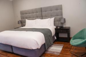 a bedroom with a large bed and a chair at THE CLAN LODGE in Mohlanapeng