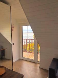 una puerta abierta a un balcón con vistas al océano en Fisheria Apartamentai en Preila