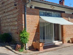 a brick house with a window with a white awning at Fontanelle in Baziège +5 photos