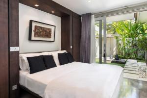 a bedroom with a large white bed with black pillows at Villa Mia in Canggu