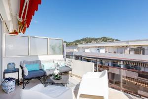 einen Balkon mit Sofa und Stühlen auf einem Gebäude in der Unterkunft XXL 2 beds with XXL terrace next to Martinez Hotel in Cannes