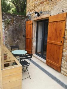 un patio con mesa y sillas y un edificio en Chambre tropicale privée au coeur d'un village calme et proche du vignoble en Vinzelles