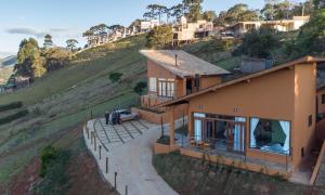 a house on a hill with people standing outside of it at Vertentes da Mantiqueira - Chalés in Santo Antônio do Pinhal