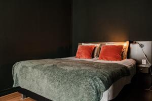a bedroom with a bed with two orange pillows at Hotel La Casa in Valkenburg