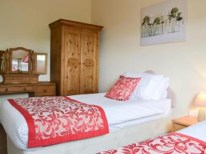 a bedroom with two beds and a dresser with a mirror at The Racecourse Lodge in Hexham