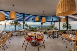 een restaurant met tafels en stoelen en uitzicht op de oceaan bij Corallium Dunamar by Lopesan Hotels - Adults Only in Playa del Inglés