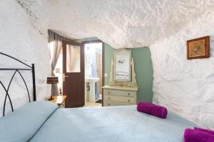a bedroom with a bed in a rock wall at Casa Cueva Gaspara in Lomo de Arico