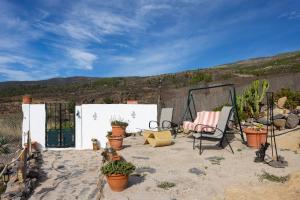 een patio met een stoel en planten in het zand bij Casa Cueva Gaspara in Lomo de Arico