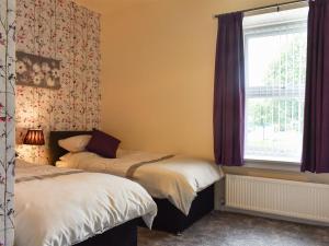 a bedroom with two beds and a window at End Cottage in Alnwick