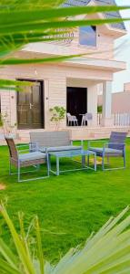 dwie ławki na trawniku przed domem w obiekcie منتجع سورا w mieście Burajda