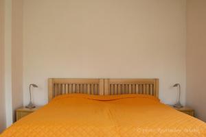 a bed with an orange bedspread and two lamps at Aviatik apartmány in Jeseník