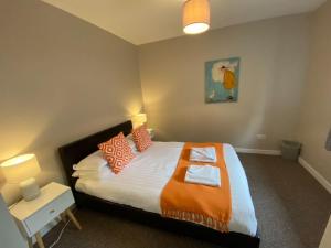 a bedroom with a large bed with an orange blanket at South Lodge - Uk31880 in Newton Stewart
