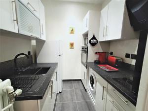 a kitchen with white cabinets and a black counter top at Studio Aix-les-Bains, 1 pièce, 2 personnes - FR-1-555-44 in Aix-les-Bains