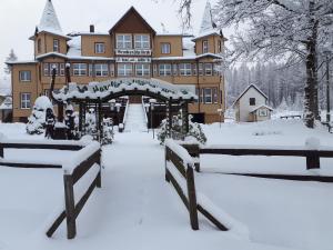 a large building covered in snow with benches in front at Hotel Brockenscheideck in Schierke