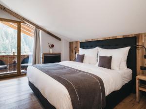 a bedroom with a large bed and a large window at VAYA Gerlos in Gerlos