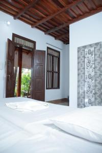 a bedroom with a white bed and a window at Malayalam Lake Resort in Alleppey