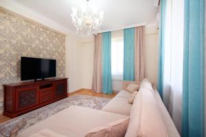 een woonkamer met een bank en een flatscreen-tv bij 2-комнатная квартира в ЖК Гагарин Парк in Alma-Ata