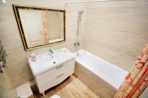 een badkamer met een wastafel, een bad en een spiegel bij 2-комнатная квартира в ЖК Гагарин Парк in Alma-Ata
