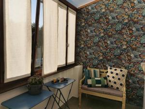 una silla y una mesa en una habitación con papel pintado en La Maison de Lucie - grande maison idéale en famille ou entre amis - jardin - parking gratuit, en Sélestat