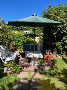 um pátio com um guarda-sol, uma mesa e cadeiras em Margate Place Guest House em Port Elizabeth
