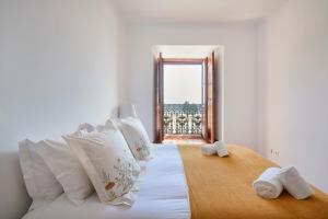 ein Schlafzimmer mit einem Bett mit weißen Kissen und einem Fenster in der Unterkunft Charming Apartment in Alfama with River View in Lissabon