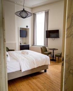 sypialnia z łóżkiem, biurkiem i telewizorem w obiekcie Heirloom Hotels - The Mansion w Gandawie