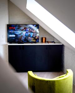 a living room with a tv and a yellow chair at Heirloom Hotels - The Mansion in Ghent