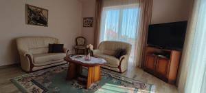 a living room with two chairs and a flat screen tv at White Column House in Diósd