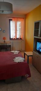 um quarto com uma cama vermelha e uma televisão em Le Gemme del Centro Storico em Potenza