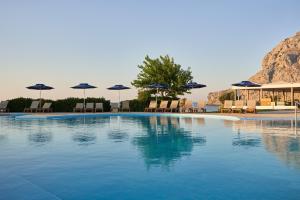 a swimming pool with chairs and umbrellas at Atlantica Kolymbia Beach in Kolymbia